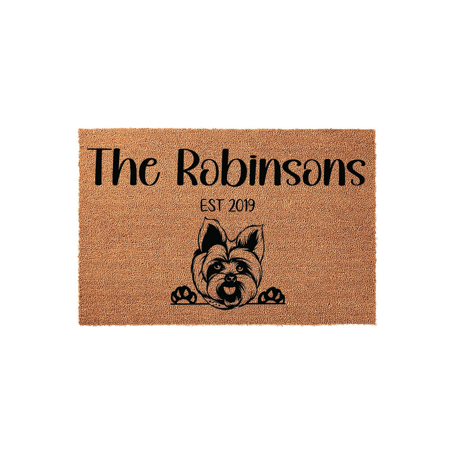 Personalized Yorkshire Terrier doormat featuring a cute dog illustration peeking over the bottom edge, with custom family name text and established year printed in black on a natural tan coir fiber background for a welcoming home