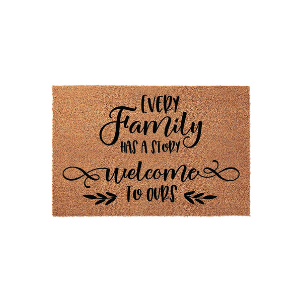 Every Family Has A Story Welcome To Ours coir doormat featuring black typography and decorative leaf accents on a natural tan fiber background, creating a warm and inviting entrance for any home front porch or entryway decor.