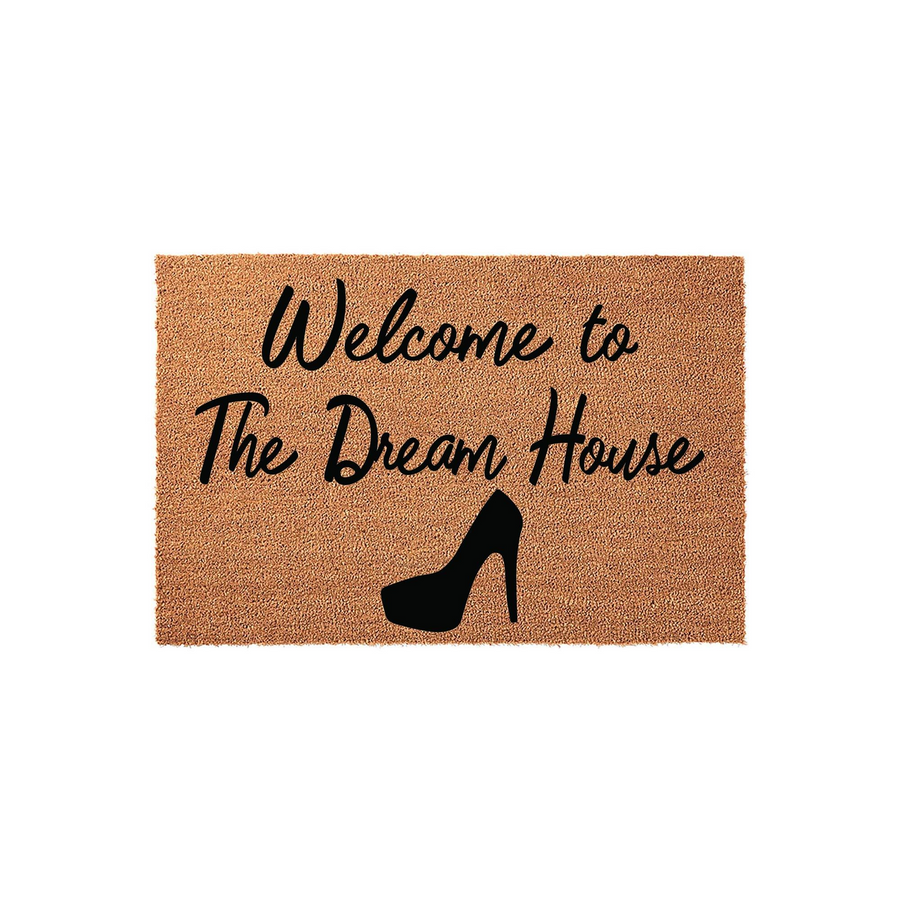 Welcome to The Dream House coir doormat featuring a black high heel shoe graphic printed on a natural tan fiber background, creating a stylish and fun entryway decor piece for any fashion lover's home front porch or apartment