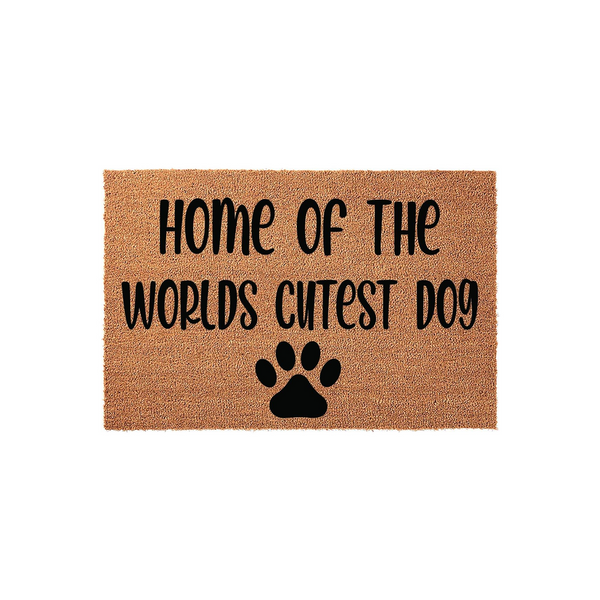 Home of the Worlds Cutest Dog coir doormat featuring a natural tan fiber texture, black printed text, and a large paw print icon centered at the bottom, displayed against a clean white background for a modern pet lover home