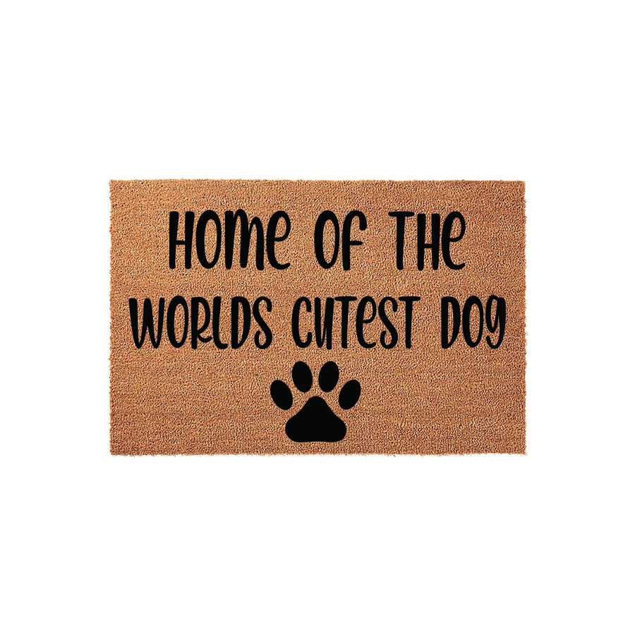 Home of the Worlds Cutest Dog coir doormat featuring a natural tan fiber texture, black printed text, and a large paw print icon centered at the bottom, displayed against a clean white background for a modern pet lover home