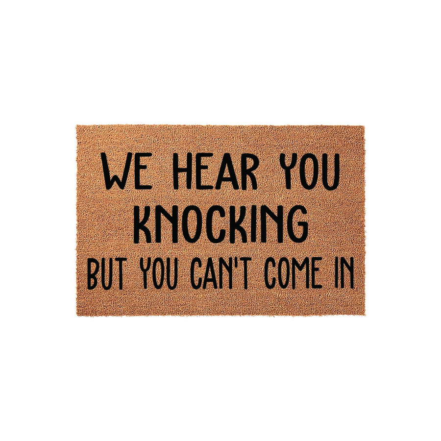 Funny We Hear You Knocking But You Can't Come In doormat featuring bold black text printed on a natural brown coir fiber mat, providing a humorous and welcoming touch to your front porch entryway decor against a clean white