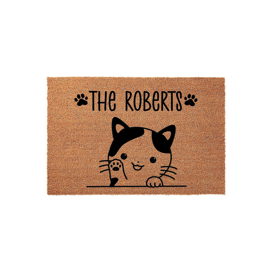 Personalized cat welcome doormat featuring a cute illustrated calico cat peeking over a line with black paw prints and custom family name text on a natural coir fiber background, creating a charming entryway decor piece for cat