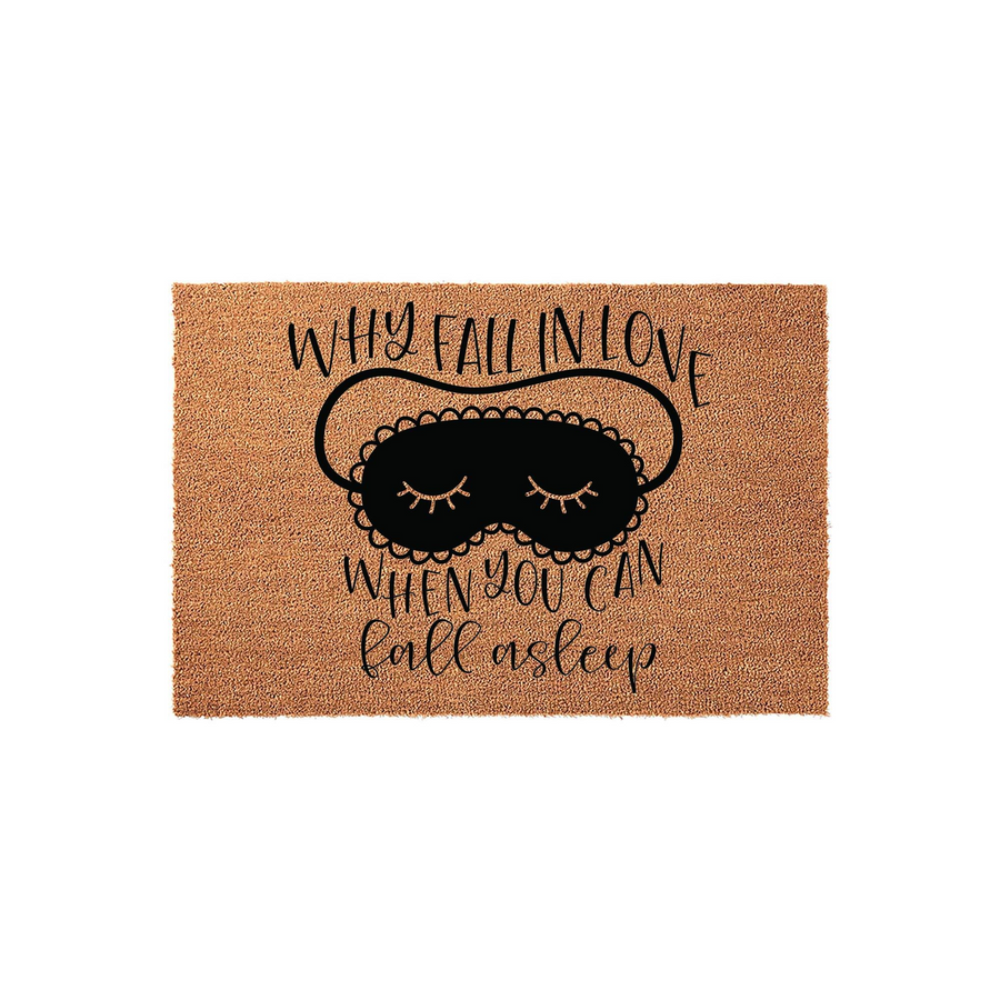 Funny Why Fall In Love When You Can Fall Asleep coir doormat featuring a black sleep mask illustration with closed eyes and eyelashes, printed on a natural brown textured coconut fiber mat against a clean white studio background.