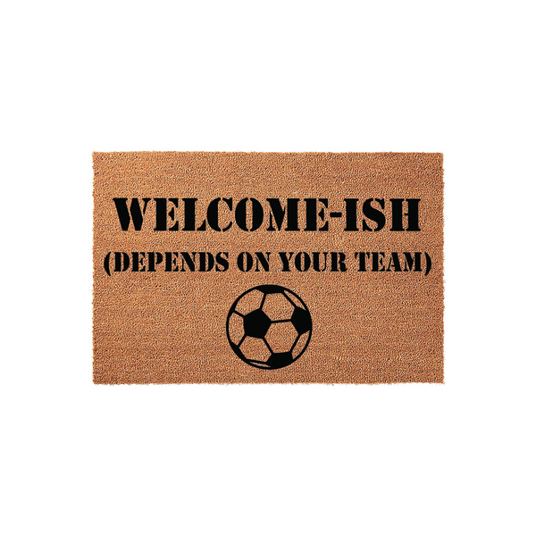 Funny Soccer Welcome Doormat featuring the text Welcome-Ish Depends On Your Team in bold black lettering above a classic soccer ball graphic, all printed on a natural brown coir fiber mat against a clean white studio background.