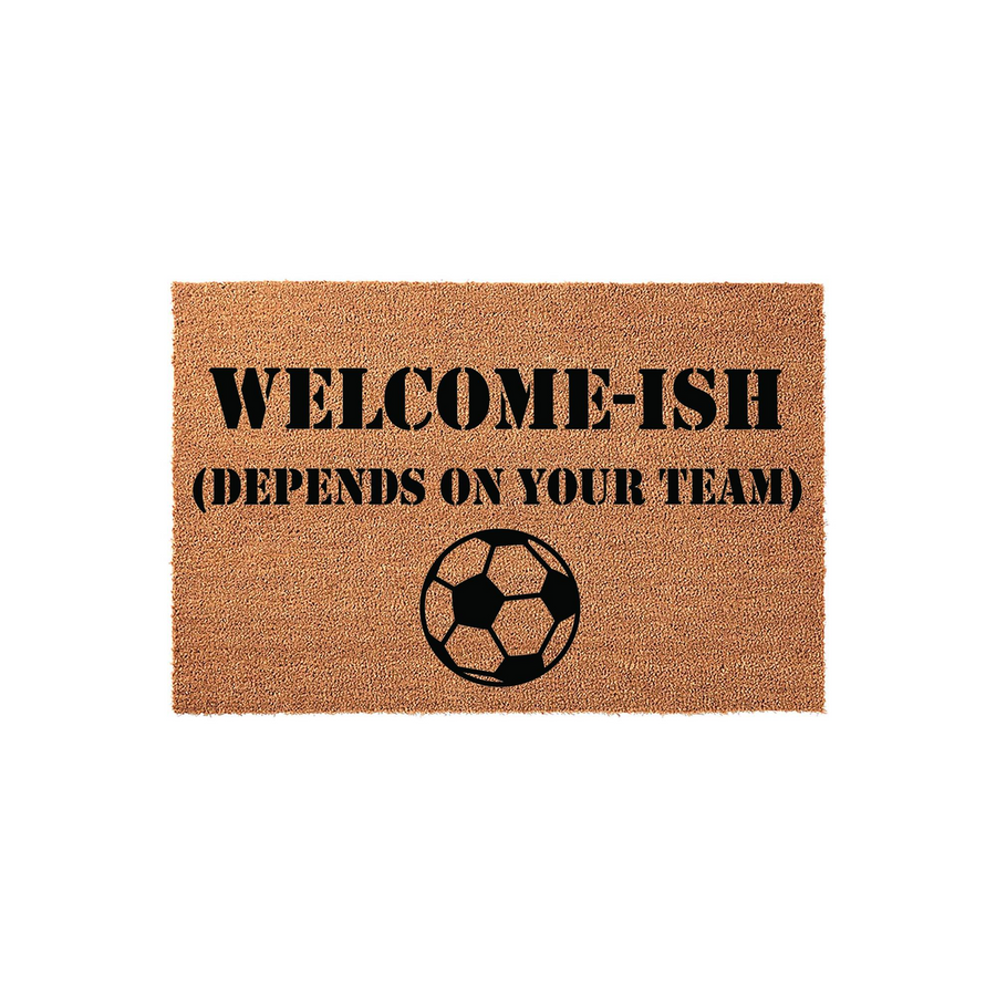 Funny Soccer Welcome Doormat featuring the text Welcome-Ish Depends On Your Team in bold black lettering above a classic soccer ball graphic, all printed on a natural brown coir fiber mat against a clean white studio background.