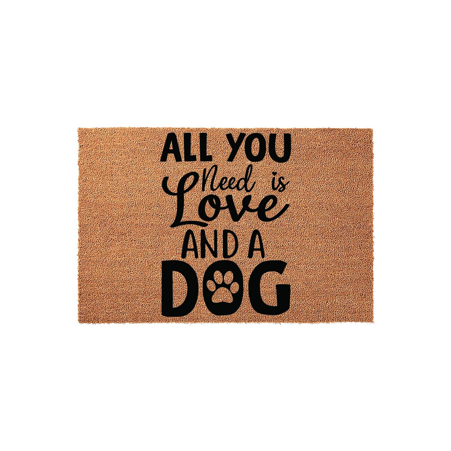 All You Need Is Love And A Dog coir doormat featuring bold black typography on a natural brown fiber background, with a cute paw print replacing the letter O in the word dog to create a charming entryway accent for any pet lover