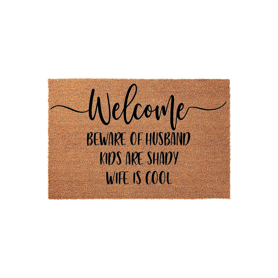 Funny Welcome Doormat featuring natural coir fibers and black text that reads Beware of Husband, Kids Are Shady, Wife Is Cool, making this a humorous and durable outdoor floor mat for a front porch or entryway with a rustic