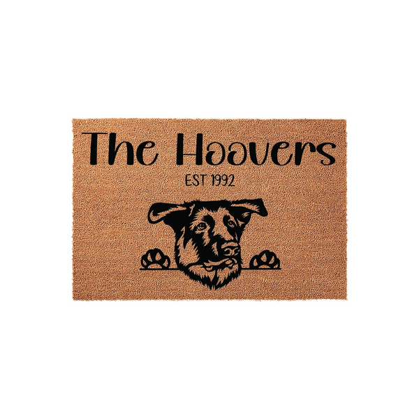 Personalized German Shepherd doormat featuring a natural coir texture with a black printed illustration of a dog peeking over the edge, customized with a family name and established year on a clean white studio background.