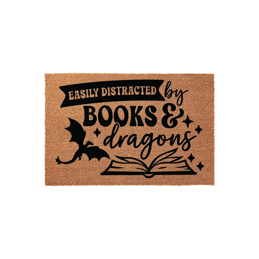 Easily Distracted by Books and Dragons coir doormat featuring a whimsical black graphic of a flying dragon and an open book, perfect for a fantasy reader's home entrance with its natural brown fiber texture and bold typography.