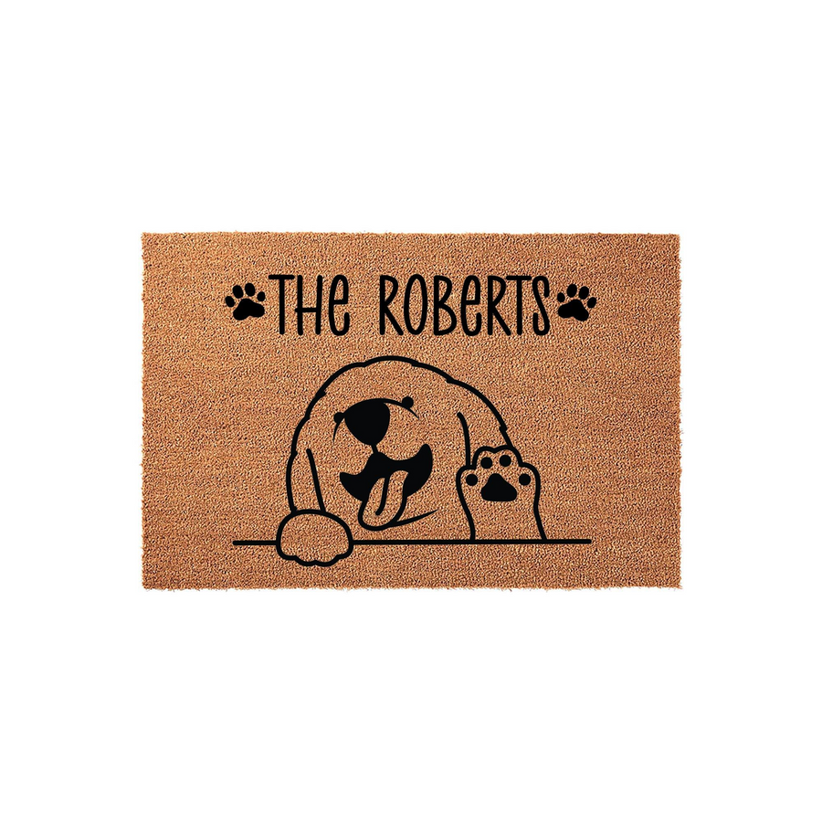 Personalized Golden Retriever doormat featuring a cute dog illustration peeking over a line with a paw raised, customized with a family name in black text on a natural coir fiber background for a welcoming front porch entrance.
