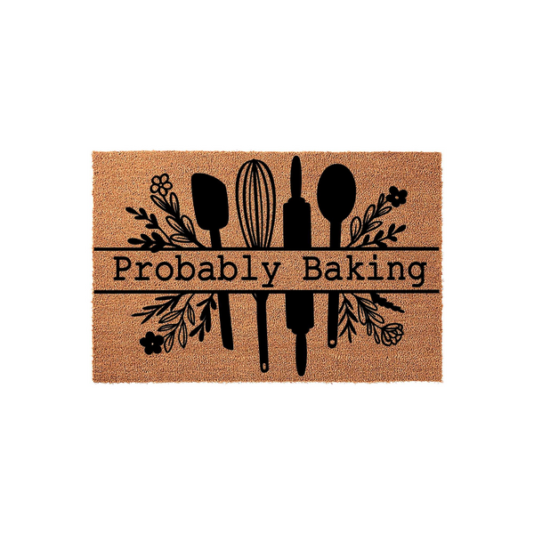Probably Baking kitchen doormat made of natural coir fiber, featuring a black printed design of a whisk, rolling pin, and spatula surrounded by floral accents on a plain white background for a rustic home decor look.