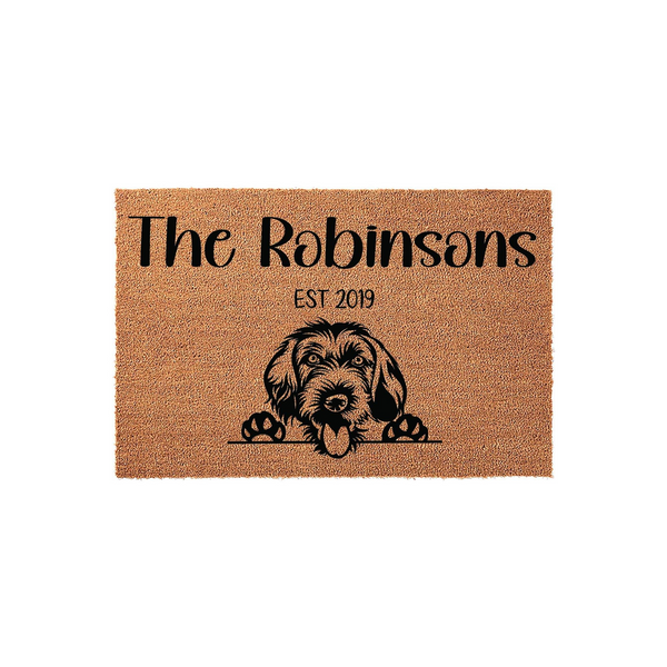 Personalized Doodle Dog Coir Doormat featuring a cute shaggy dog illustration, custom family name text, and an established year date, all printed in black ink on a natural brown textured fiber mat against a clean white background.