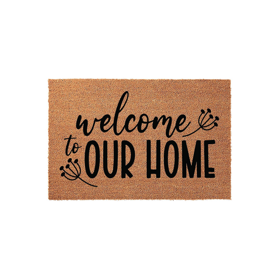 Welcome to Our Home coir doormat featuring a natural tan fiber texture and bold black typography, accented by delicate floral line art illustrations on a clean white background for a modern farmhouse entryway decor style.
