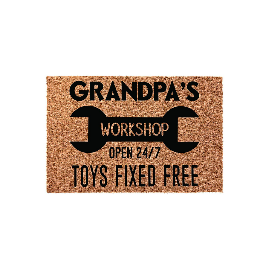 Grandpa's Workshop doormat featuring a large black wrench graphic and bold text that reads Open 24/7 and Toys Fixed Free, set against a natural tan coir fiber background for a rustic garage or workshop entrance decor style.