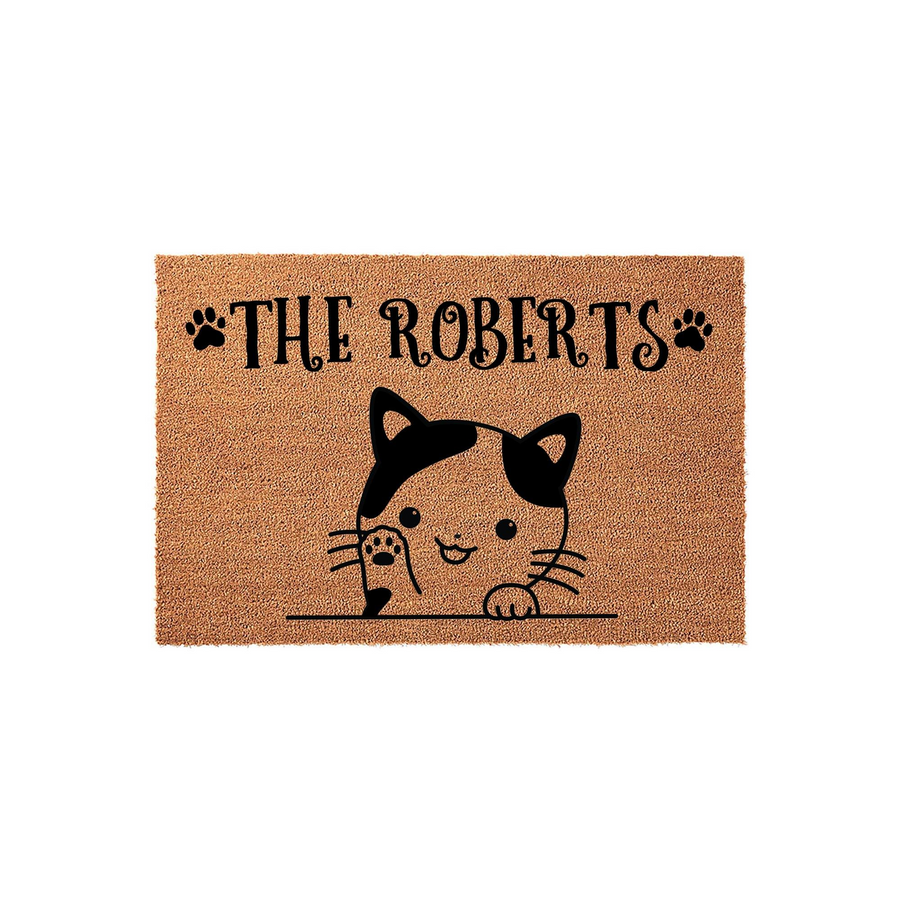 Personalized cat doormat featuring a cute illustrated calico cat peeking over a line, customized with a family name in black text and paw print accents on a natural coir fiber background for a charming entryway decor piece.