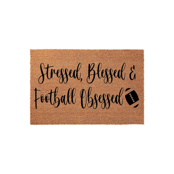 Stressed Blessed and Football Obsessed coir doormat featuring bold black cursive lettering and a small football graphic on a natural tan textured background, perfect for a sports fan entryway or a front porch decor update.