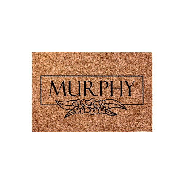Personalized family name coir doormat featuring a clean rectangular frame and a delicate floral illustration printed in black ink on a natural brown coconut fiber background, creating a welcoming entrance for any modern home