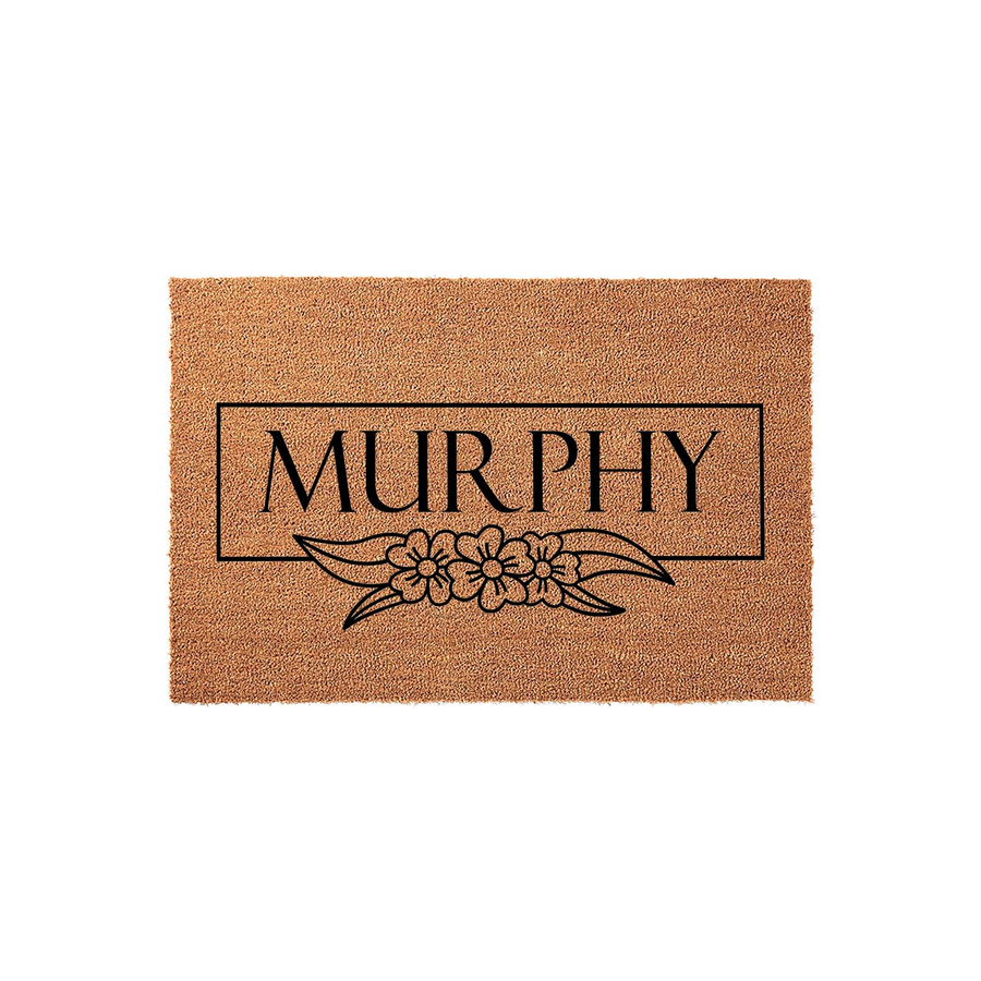 Personalized family name coir doormat featuring a clean rectangular frame and a delicate floral illustration printed in black ink on a natural brown coconut fiber background, creating a welcoming entrance for any modern home