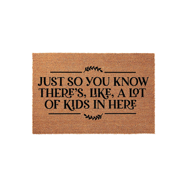 Funny Kids Welcome Doormat made of natural coir fiber, featuring the black printed text Just So You Know There Is Like A Lot Of Kids In Here with decorative leaf accents on a plain white background for a modern home entryway
