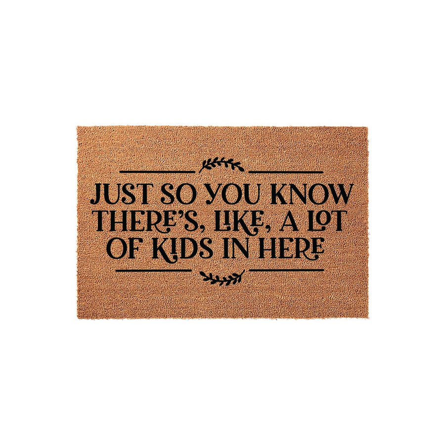 Funny Kids Welcome Doormat made of natural coir fiber, featuring the black printed text Just So You Know There Is Like A Lot Of Kids In Here with decorative leaf accents on a plain white background for a modern home entryway