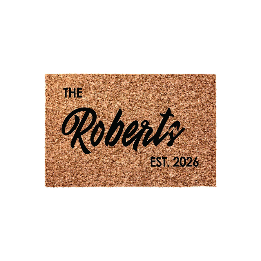 Personalized family name coir doormat featuring a natural tan fiber texture with bold black lettering that displays a custom last name and an established year, creating a welcoming entrance for any home or front porch decor.