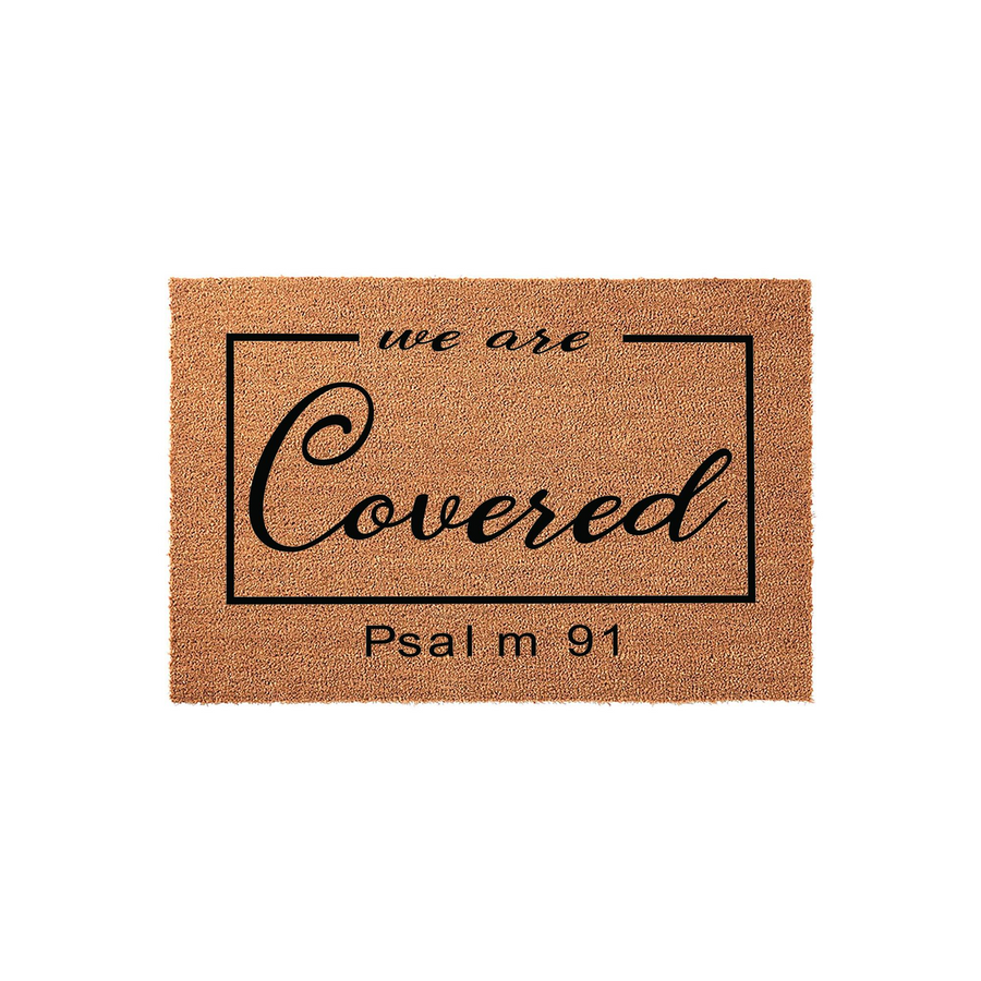 We Are Covered Psalm 91 Coir Doormat featuring a natural tan fiber texture with black script lettering inside a rectangular border, providing a welcoming and faith-inspired entrance decor piece for your front porch or home