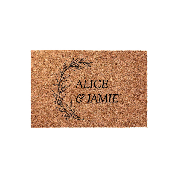 Personalized coir doormat featuring a minimalist black botanical wreath design on a natural brown fiber background, providing a welcoming entrance for a home with custom text printed in a clean serif font for a modern farmhouse