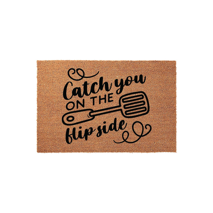 Catch You On The Flip Side Coir Doormat featuring a black printed spatula graphic on a natural tan fiber background, creating a fun and welcoming entrance mat for any kitchen or home entryway that adds a touch of humor to your