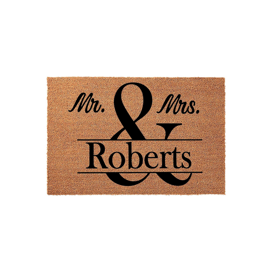 Personalized Mr. and Mrs. last name coir doormat featuring a large black ampersand design printed on a natural brown fiber background, making a classic wedding or housewarming entrance decor piece for a newlywed couple's front
