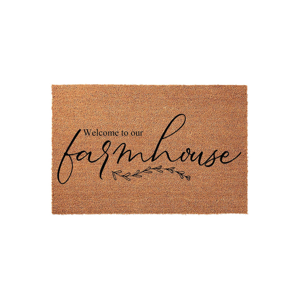 Farmhouse Welcome Doormat featuring a natural coir texture with black script lettering that reads Welcome to our farmhouse, accented by a delicate botanical leaf design centered on a clean, plain white studio background.