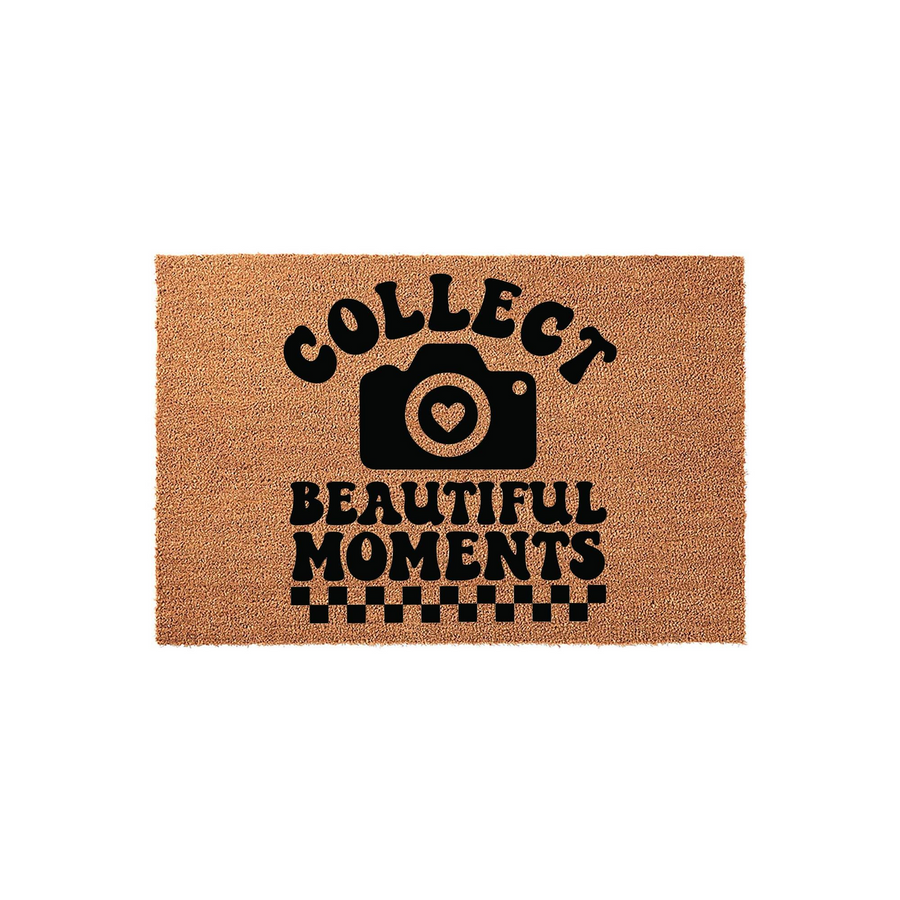 Collect Beautiful Moments photography doormat made of natural coir fiber, featuring a black camera icon with a heart lens and a checkered border design on a plain white background for a modern home entryway or photography studio