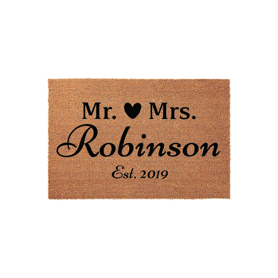 Personalized Mr. and Mrs. coir doormat featuring a black heart icon, a custom family name, and an established year, presented on a clean white background for a classic wedding or housewarming entrance decor style.