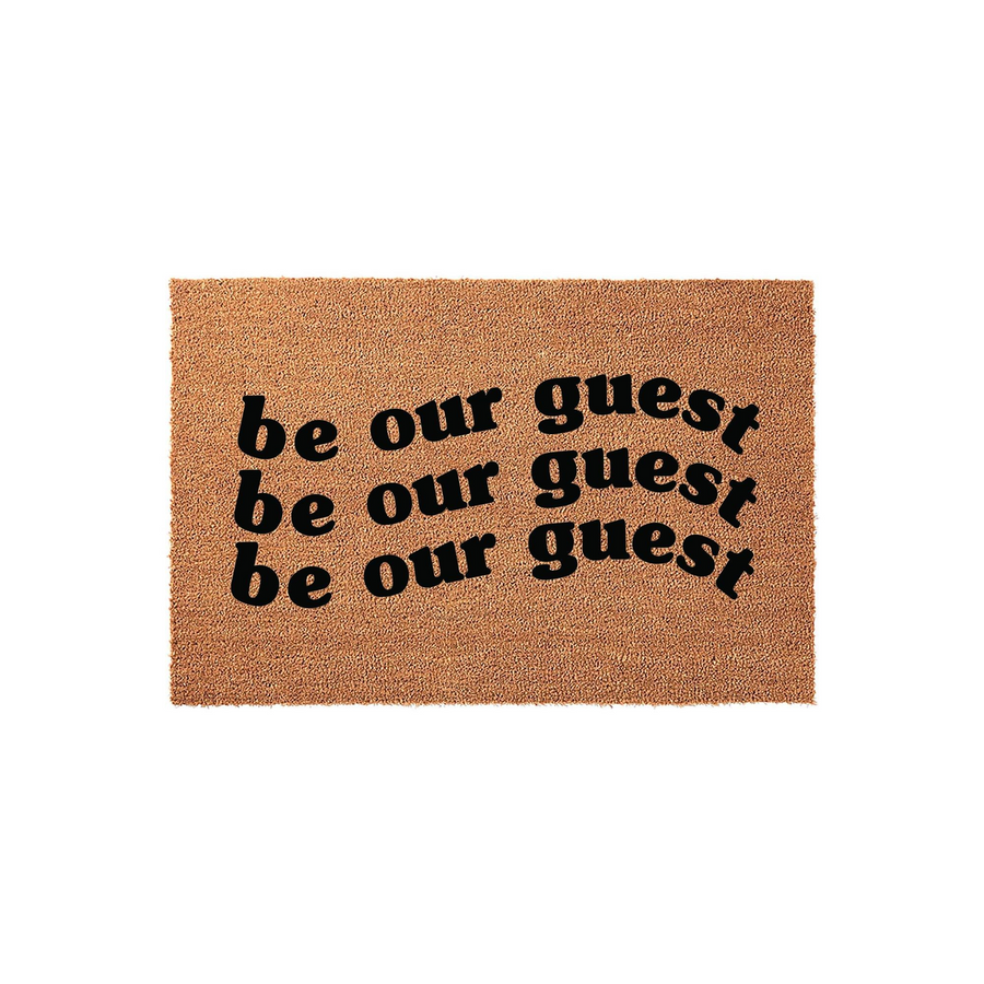Be Our Guest coir doormat featuring a natural brown fiber texture and bold black lettering that repeats the phrase three times, creating a welcoming and stylish entrance piece for any home front porch or entryway decor.
