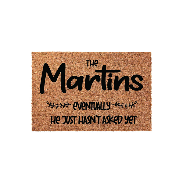 Personalized coir doormat featuring a humorous message about a family name and the phrase he just hasn't asked yet, displayed on a clean white background to showcase the natural brown fiber texture and bold black custom