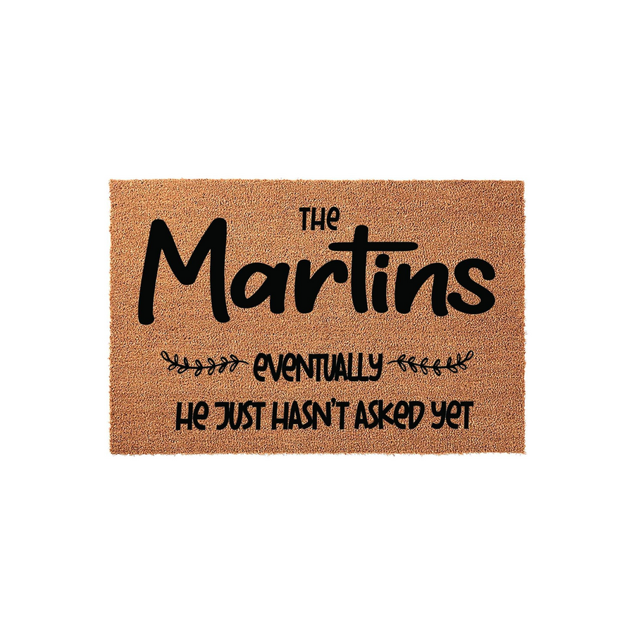 Personalized coir doormat featuring a humorous message about a family name and the phrase he just hasn't asked yet, displayed on a clean white background to showcase the natural brown fiber texture and bold black custom