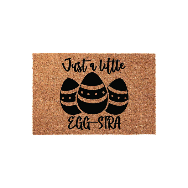 Easter Egg Coir Doormat featuring a natural brown fiber texture with black printed text that reads Just a little EGG-STRA above three decorative patterned Easter eggs, creating a festive spring welcome for your front porch