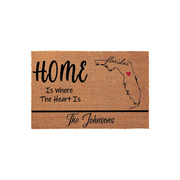 Personalized Florida state map coir doormat featuring the text Home Is Where The Heart Is with a red heart icon over the state, providing a custom entryway welcome mat for a family home on a clean white studio background.