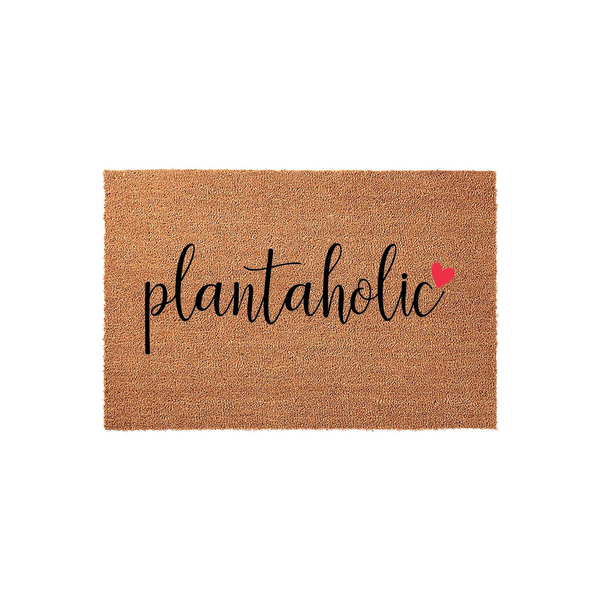 Plantaholic coir doormat featuring a natural brown fiber texture and bold black cursive lettering that reads plantaholic, accented by a small red heart icon on a clean white background for a modern home entryway decor aesthetic.