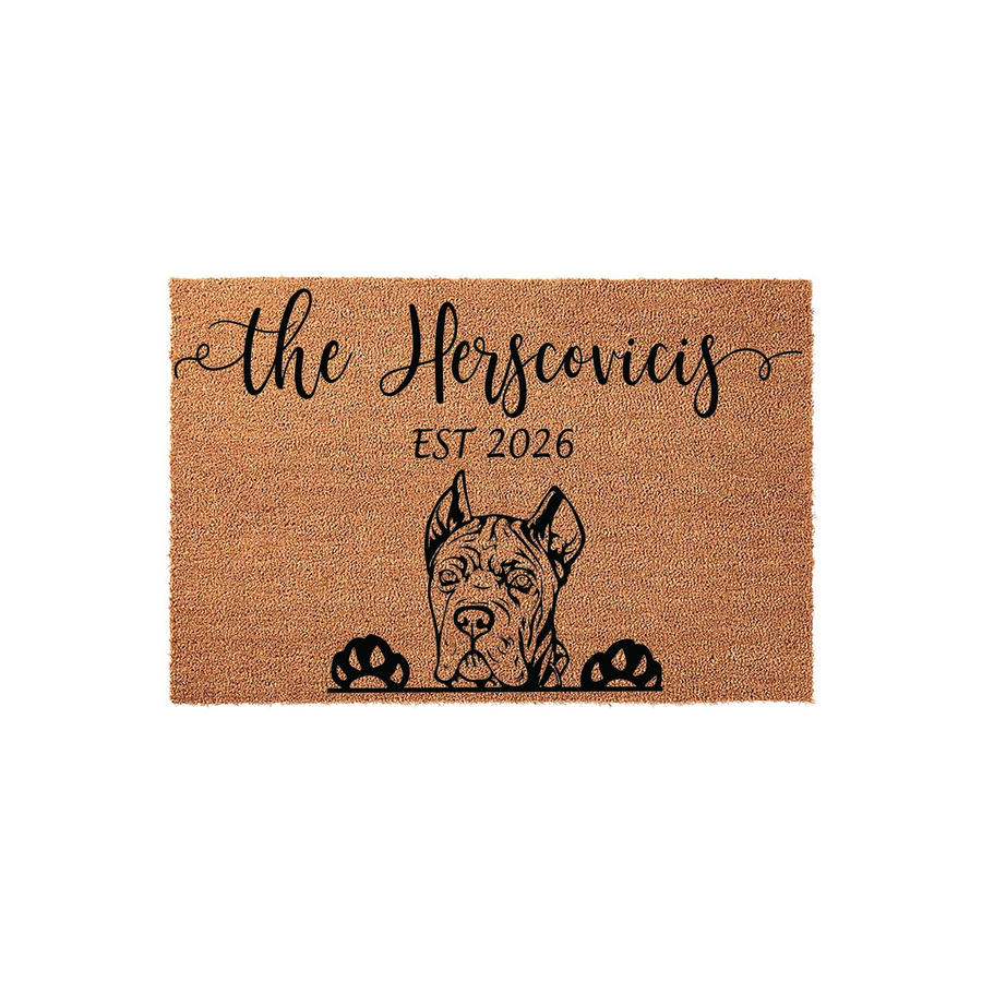 Personalized Cane Corso doormat featuring a natural coir texture with a black printed illustration of a dog peeking over its paws, customized with a family name and established year on a clean white studio background.