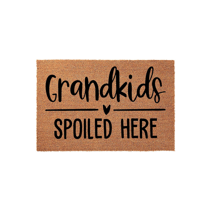 Grandkids Spoiled Here coir doormat featuring natural brown coconut fiber texture and bold black lettering, designed as a fun entryway accent for a grandparent home with a small heart icon centered between the lines of text.