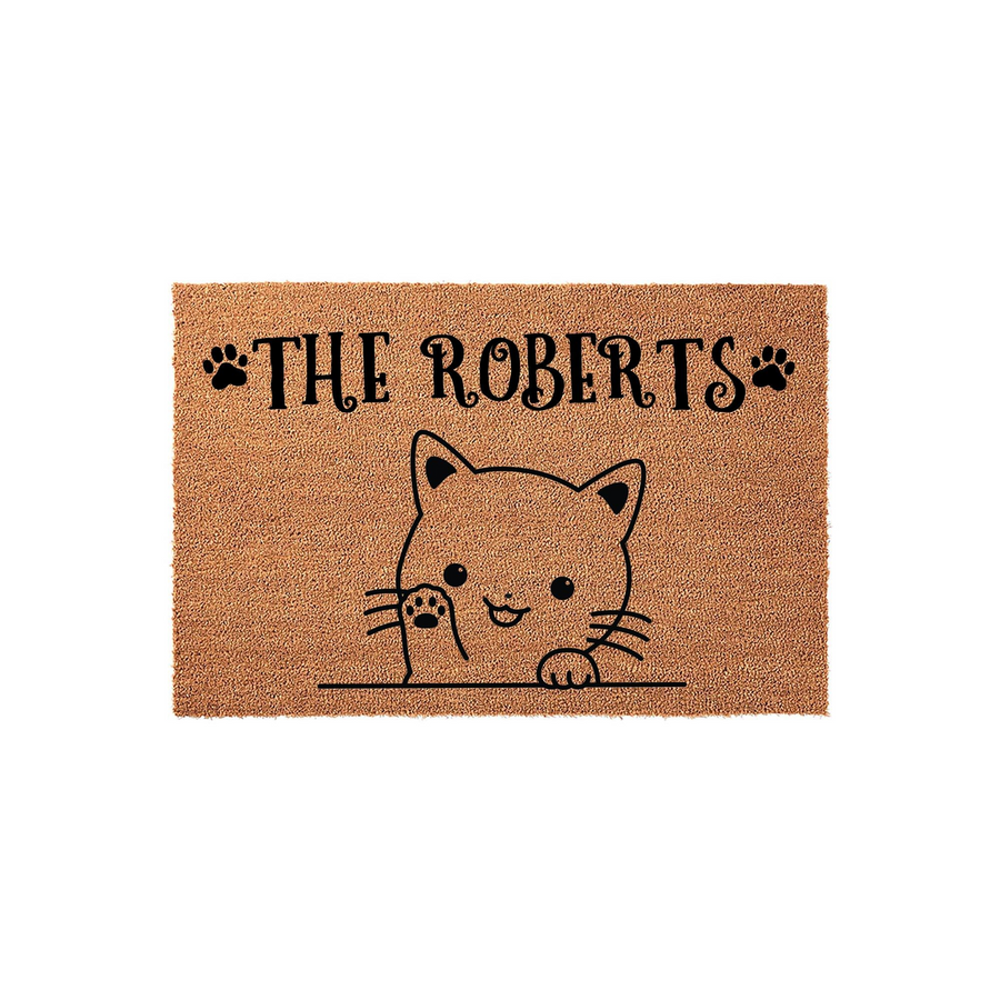 Personalized cat doormat featuring a cute illustrated kitten peeking over a line with its paw raised, set against a natural coir background with customizable family name text and decorative black paw prints on either side.