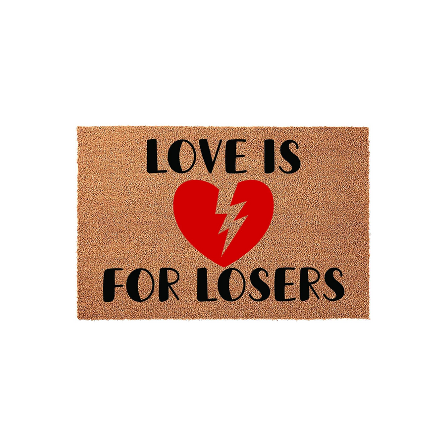 Love Is For Losers coir doormat featuring a bold red broken heart graphic with a lightning bolt crack in the center, set against a natural tan textured fiber background with black typography for a humorous and edgy home entryway