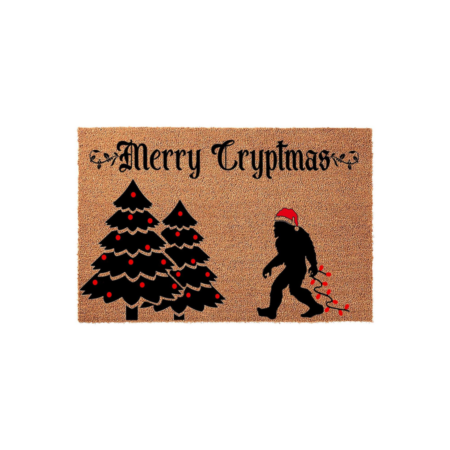 Merry Cryptmas Bigfoot Christmas doormat featuring a silhouette of the legendary creature wearing a Santa hat and carrying red holiday lights next to two decorated pine trees on a natural coir fiber background for festive home