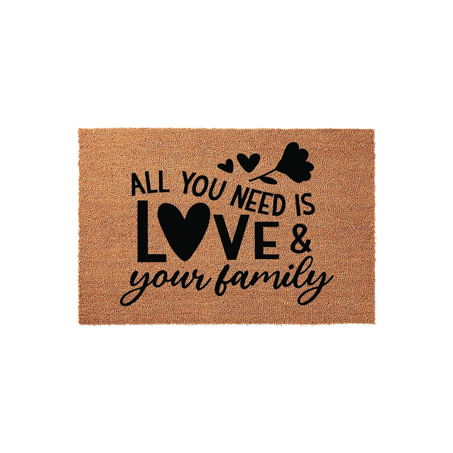 All You Need Is Love and Your Family coir doormat featuring a natural brown fiber texture with bold black text and a decorative heart and flower design, creating a warm and inviting entrance for any home or front porch decor.