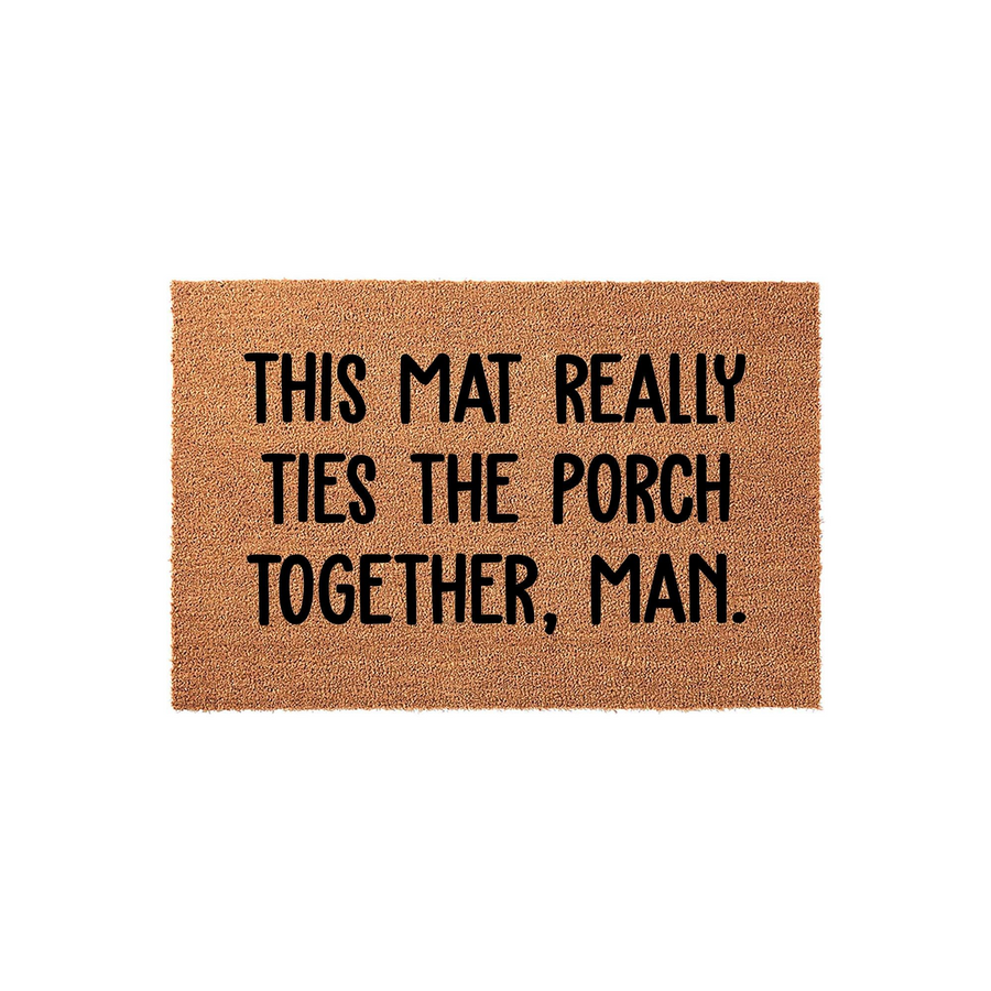 Funny Coir Doormat with the text This Mat Really Ties The Porch Together Man printed in bold black lettering, featuring a natural brown fiber texture that adds a humorous and welcoming touch to any front entryway or home porch
