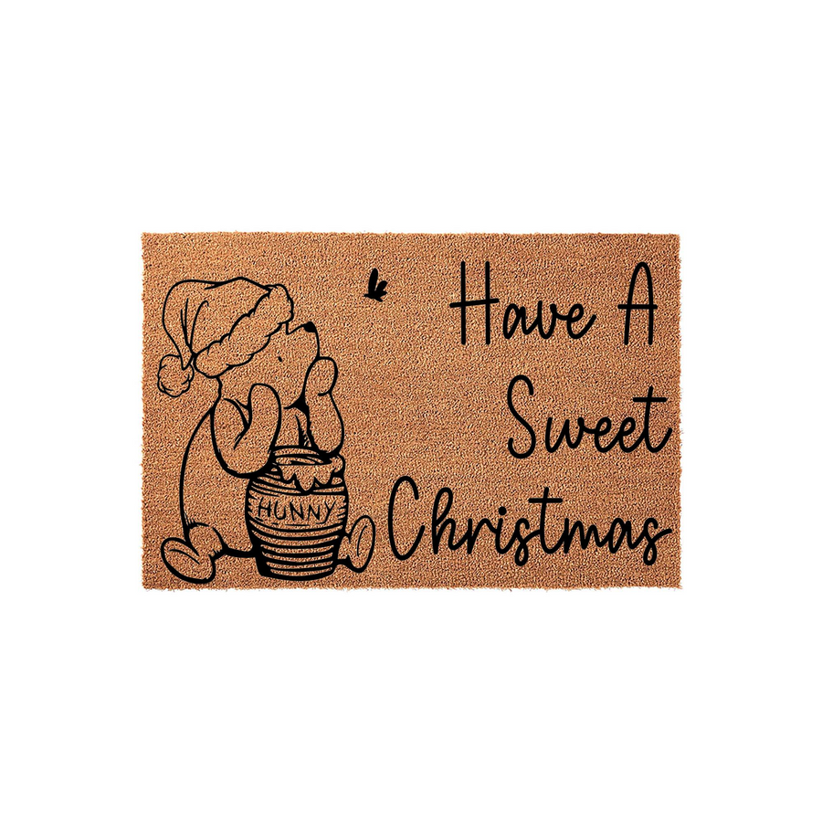 Winnie the Pooh Christmas coir doormat featuring a cute bear wearing a Santa hat next to a honey pot, with the text Have A Sweet Christmas printed in black script on a natural brown fiber background for a festive holiday entryway.