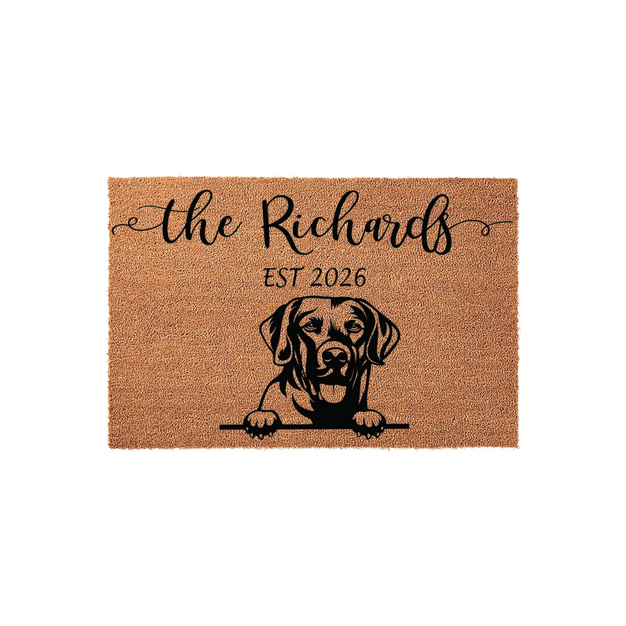 Personalized Labrador Retriever coir doormat featuring a black illustration of a dog peeking over a line, customized with a family name and established year printed in elegant black script and serif fonts on a natural brown fiber