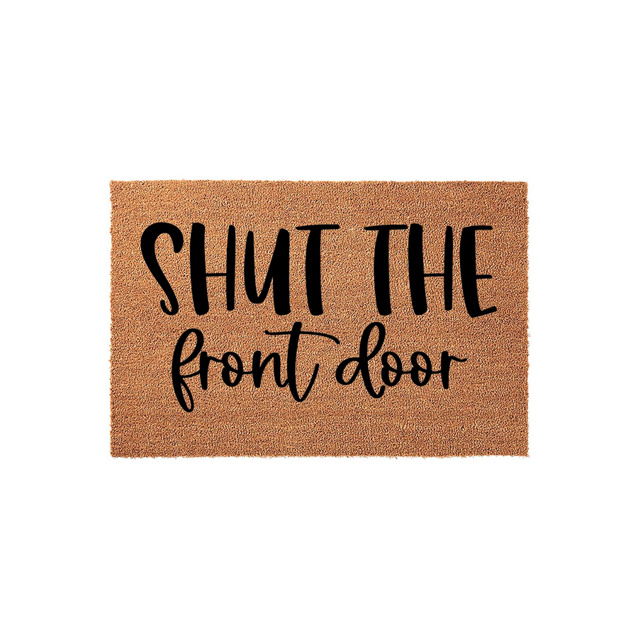 Shut the front door coir doormat featuring a natural tan fiber texture and bold black lettering in a mix of modern sans-serif and script fonts, creating a humorous and welcoming entrance piece for your home porch or entryway
