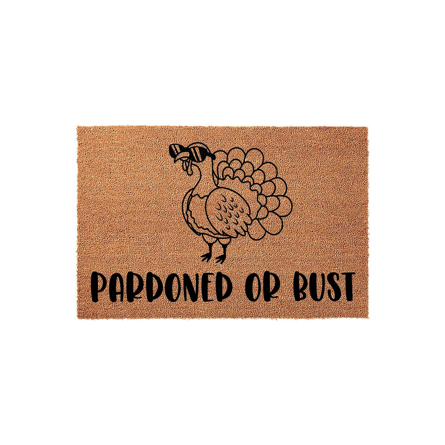 Pardoned or Bust Thanksgiving doormat featuring a cute turkey wearing black sunglasses, printed in bold black ink on a natural tan coir fiber mat that adds a fun and festive touch to your holiday home entryway decor.